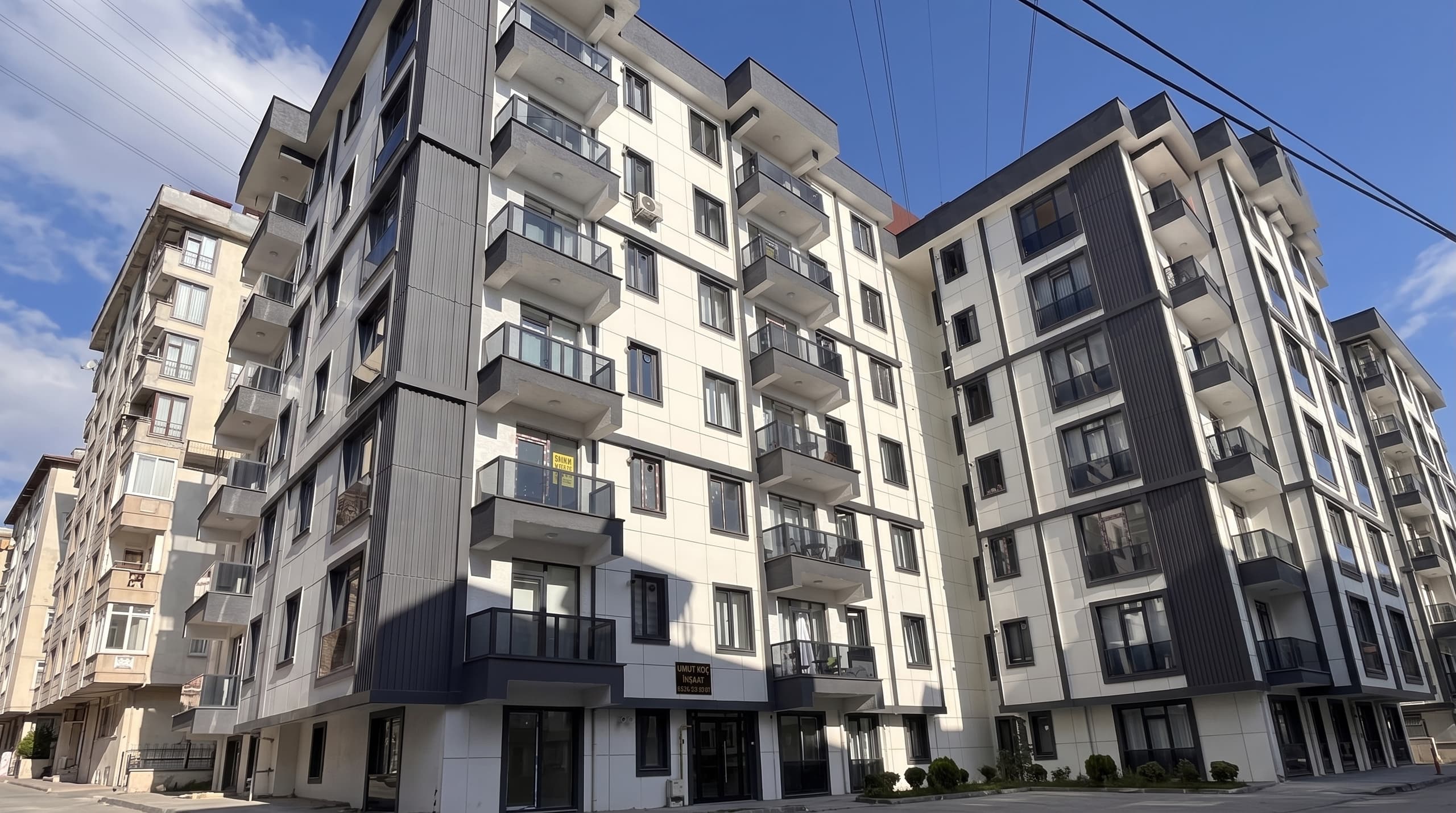 Gri ve beyaz kompozit cepheli, çok katlı modern konut bloğu